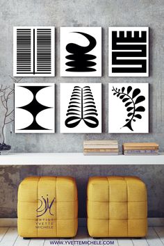 four black and white art pieces hanging on the wall above a table with two yellow chairs