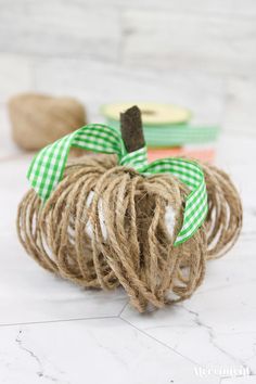 twine wrapped pumpkins with green and white plaid ribbon tied around them on a marble surface