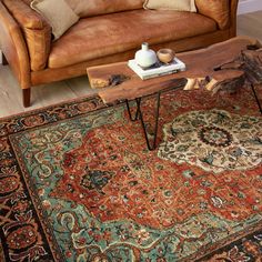 a living room with a couch, coffee table and rug on the floor in front of it