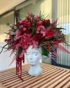 a vase filled with red flowers on top of a wooden table