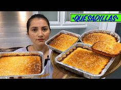 a woman holding four pans of food on top of a wooden table with the words quesadillas in front of her