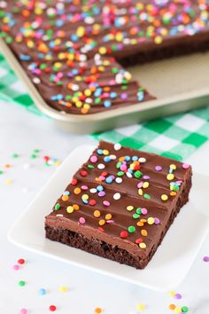 a piece of chocolate cake with sprinkles on a plate next to a tray