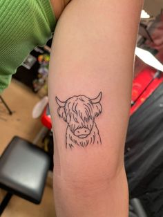 a small black and white cow tattoo on the arm