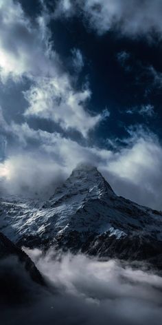 a mountain covered in clouds under a cloudy sky