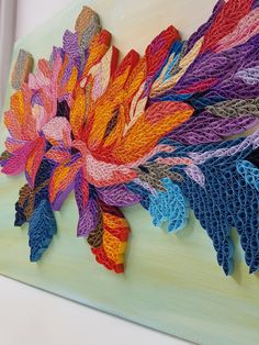 an art piece made out of crochet and yarn with colorful flowers on it