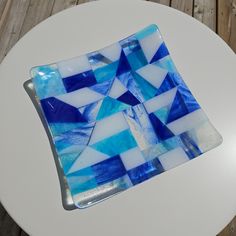 a blue and white glass plate sitting on top of a wooden table next to a cup