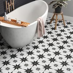 a bath tub sitting on top of a tiled floor next to a wooden stool and potted plant