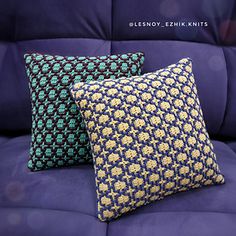 two blue and yellow pillows sitting on top of a purple couch next to each other