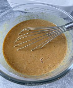 a glass bowl filled with batter and whisk