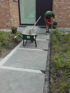 a person with a wheelbarrow and shovel in front of a brick building