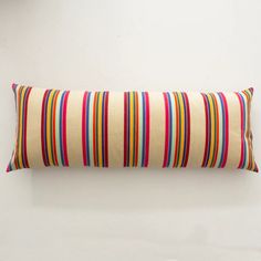 a colorful striped pillow on a white wall