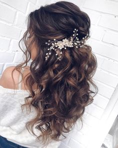 a woman wearing a hair comb with flowers on it's head, in front of a brick wall