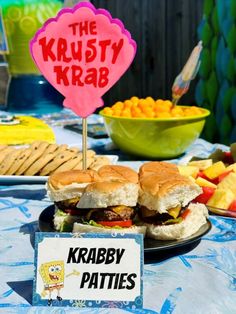 a table topped with two burgers next to a sign that says the krusty krab