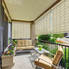 an outdoor covered porch with furniture and blinds on the outside wall, along with potted plants