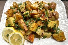 a white plate topped with potatoes and lemon wedges