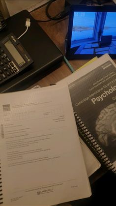 an open book sitting on top of a desk next to a laptop computer and calculator