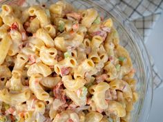 a glass bowl filled with macaroni salad on top of a white table cloth