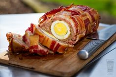 bacon wrapped meat with an egg in it on a cutting board next to a knife