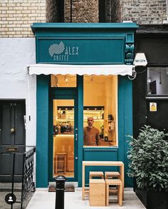 a man standing in the window of a restaurant with green and white awnings