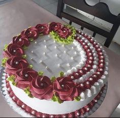 a cake decorated with red and green flowers on a white platter, sitting on top of a table