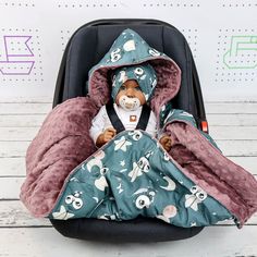 a baby doll in a car seat covered with a blanket