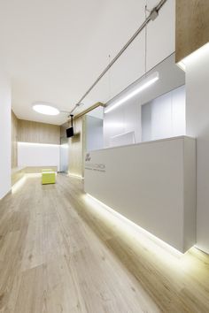 an empty room with wooden floors and white walls, illuminated by recessed light fixtures