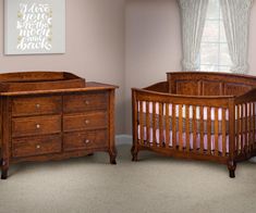 two wooden cribs in a room with pink walls and carpeted flooring