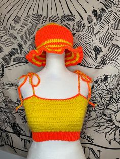 a white mannequin with a yellow and orange top on it's head