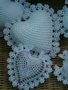 white lace doily with hearts on it sitting on a wicker tablecloth next to two vases