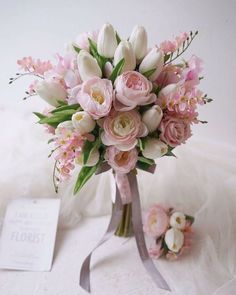 a bouquet of pink and white flowers sitting on top of a table next to a card