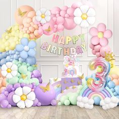 a birthday cake surrounded by balloons and flowers