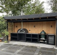 an outdoor bbq with two large grills on the side and shelves underneath it