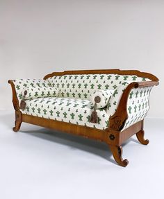 a wooden couch with green and white patterned fabric on it's armrests