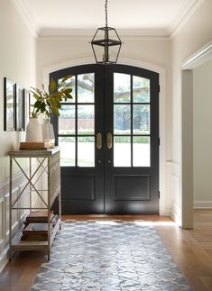 an entryway with black double doors and a rug on the floor next to it