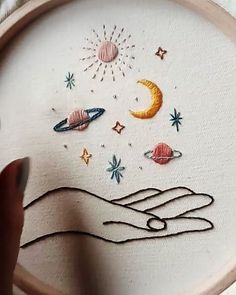 someone is working on an embroidery project with their hand and the moon in the sky