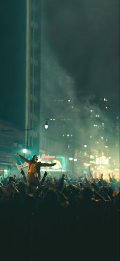 a man standing on top of a stage with his arms in the air while people watch