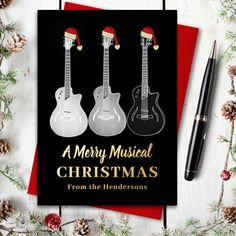 a merry musical christmas card with three guitars on it and a pen next to it