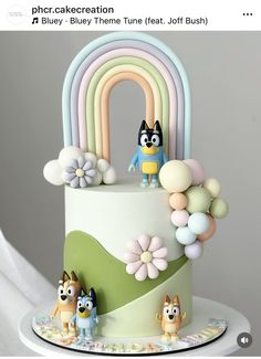 the cake is decorated with cartoon characters and rainbows on it's top tier