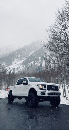 a white truck parked on the side of a road in front of snow covered mountains