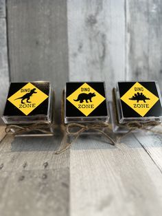 three square coasters sitting on top of a wooden table covered in black and yellow stickers