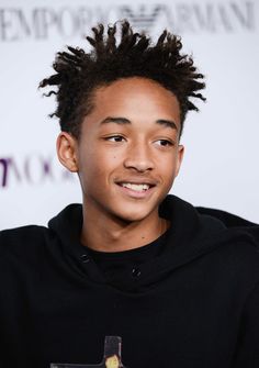 a young man with dreadlocks smiles at the camera