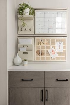 a desk with drawers and office supplies on the top, along with a plant in a white vase