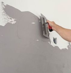 a person using a paint roller to paint a wall with gray paint and white walls