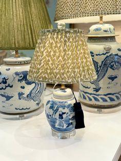 three blue and white vases with lamps on top of them, sitting on a table