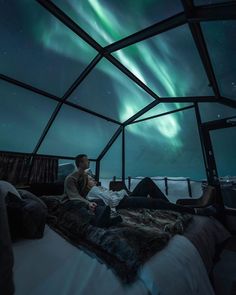 a man sitting on top of a bed under the aurora bore