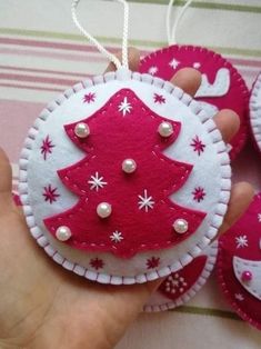 a hand holding a red and white ornament with a christmas tree on it