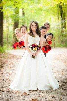 a bride and her bridals posing for a photo in the woods with their bouquets