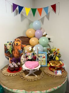 a table topped with a cake and lots of balloons