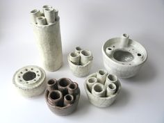 several white vases with holes in them sitting next to each other on a table