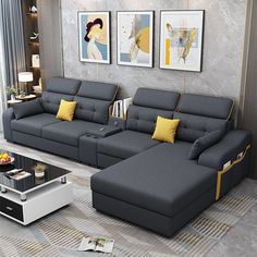 a modern living room with grey couches and yellow pillows on the floor, two framed pictures above them